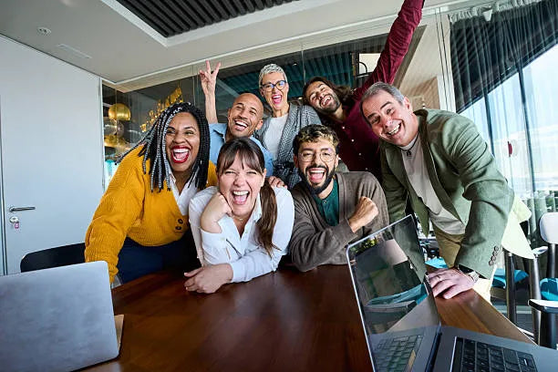 A diverse group of people joyfully celebrating together in an office setting