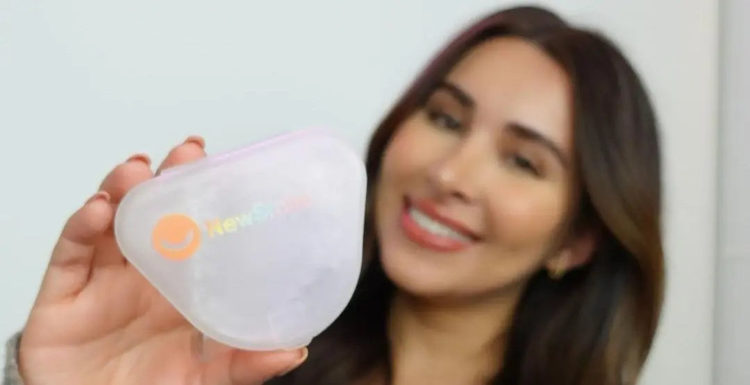 Smiling woman holding a clear retainer case after orthodontic treatment – NewSmile custom retainers